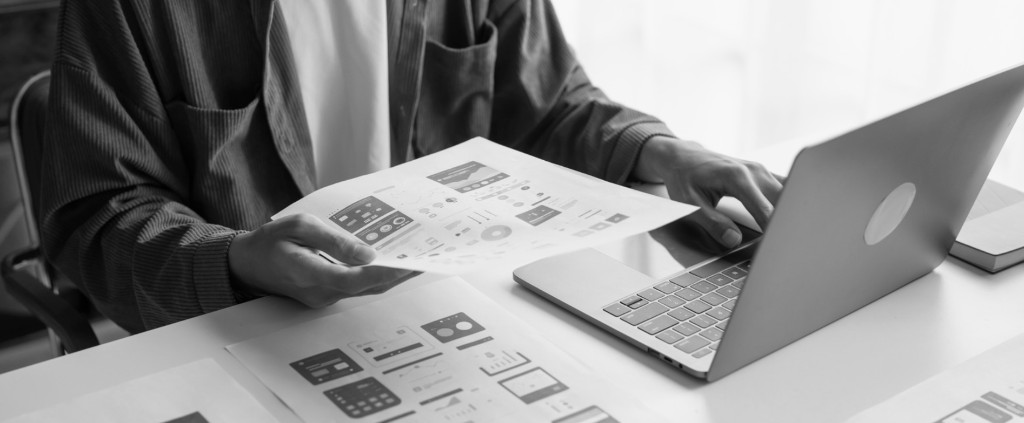 Developer reviewing UI wireframes and website layouts on a laptop