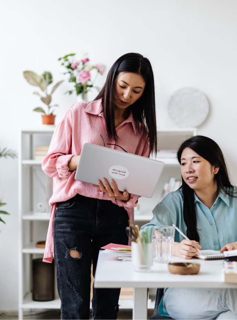 Designer and client reviewing work together at a desk with a laptop