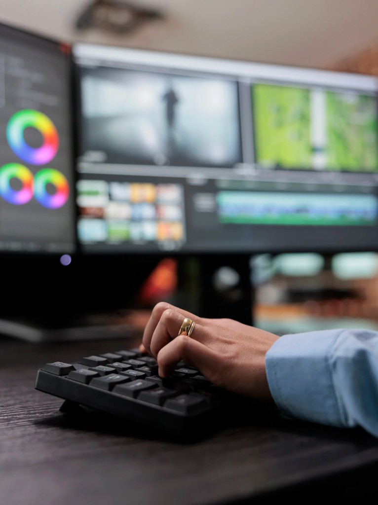 Video editor working at a keyboard with color grading and timeline tools visible on screen